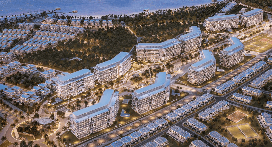 Aerial view of modern architecture with illuminated buildings and surrounding greenery near a waterfront.