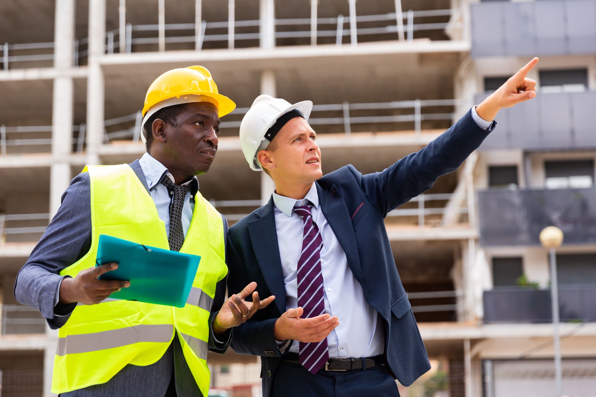 Foreman showing builder something at the construction site by pointing hand